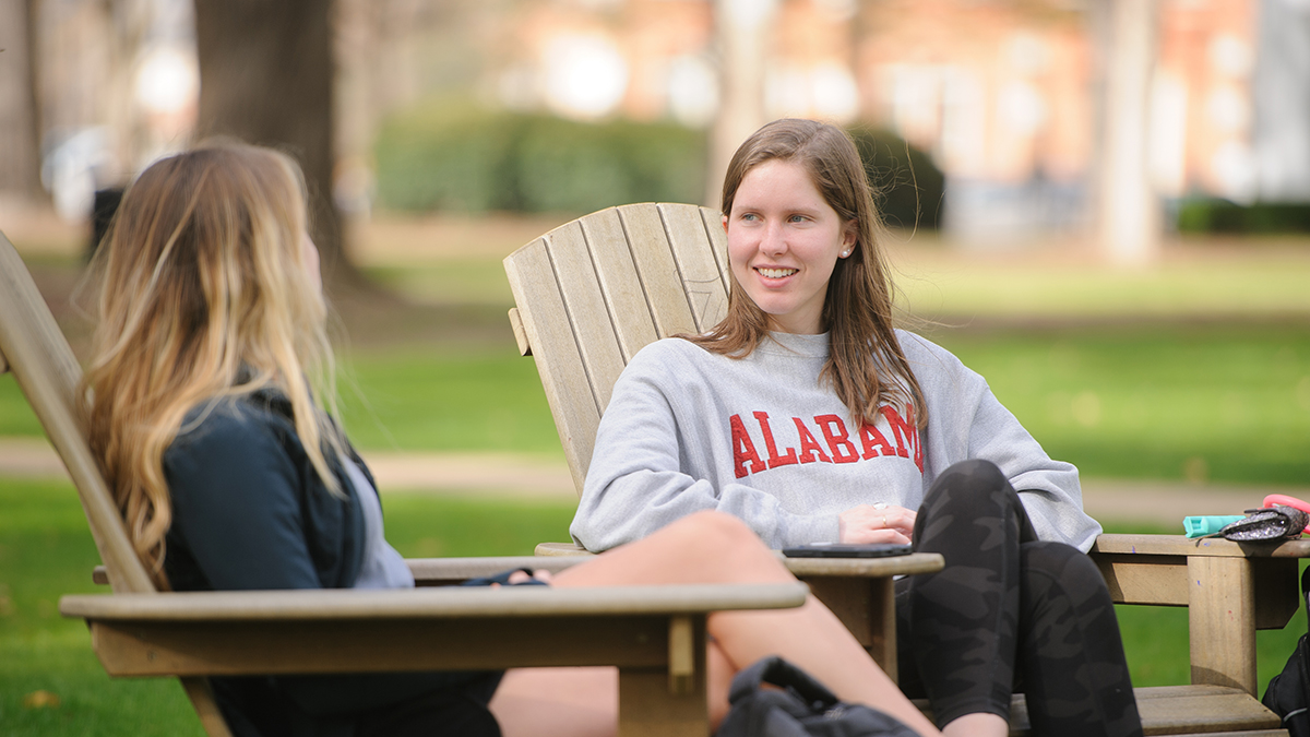 two students sitting on Adirondack chairs